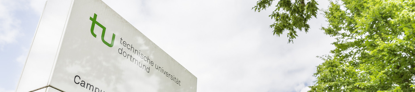 Ein weißes Hinweisschild zum Campus Süd steht neben grünen Bäumen.